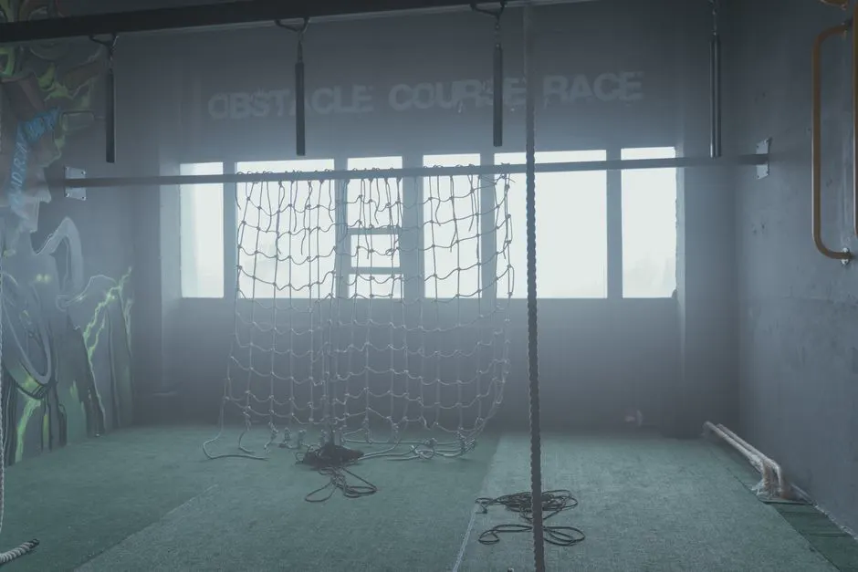Athlete crossing an indoor obstacle course with a cargo net